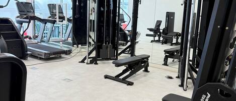 A gym with treadmills, weight machines, and benches.
