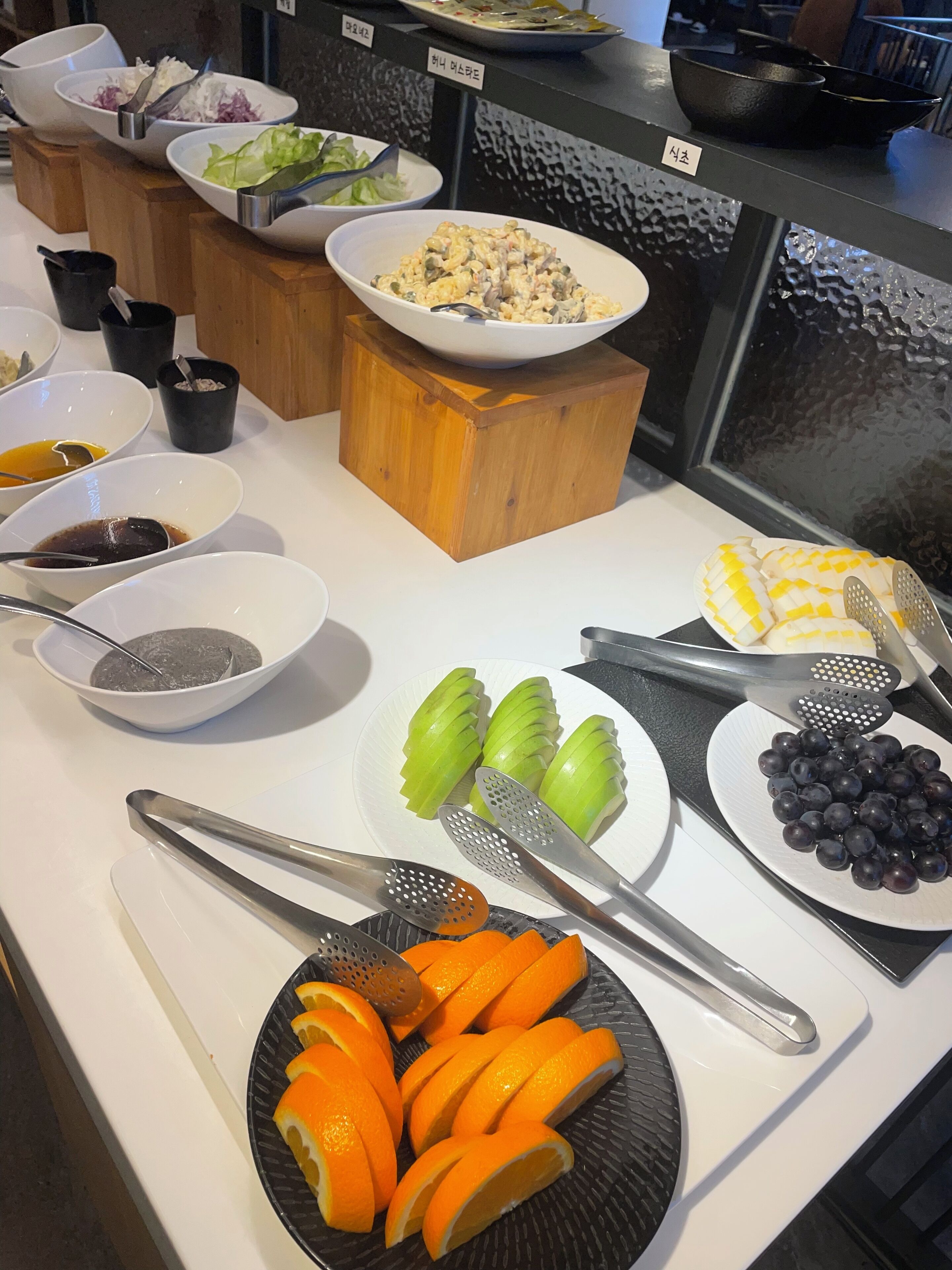 A buffet with various food items including fruits, salads, and a bowl of soup.