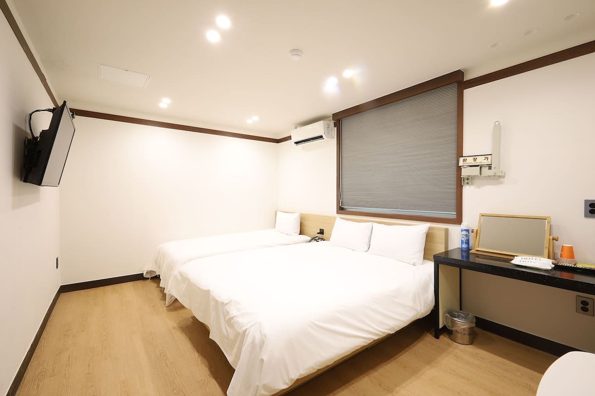 Habitación de hotel con dos camas, un escritorio, un espejo, un televisor y un equipo de aire acondicionado.