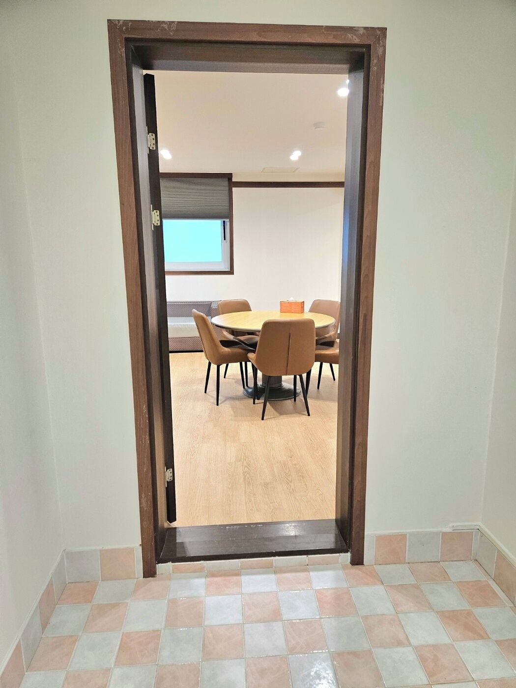 Una sala conferenze con un tavolo rotondo e sei sedie, uno schermo per proiettore e una porta che dà su un'altra stanza.