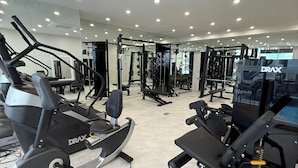 A gym with various exercise equipment, including treadmills and weight machines, and a mirrored wall. - JB Plus Hotel (Busan)