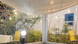 An outdoor dining area with tables and chairs, a table set with food and drinks, and a view of the cityscape in the background. - JB Plus Hotel (Busan)