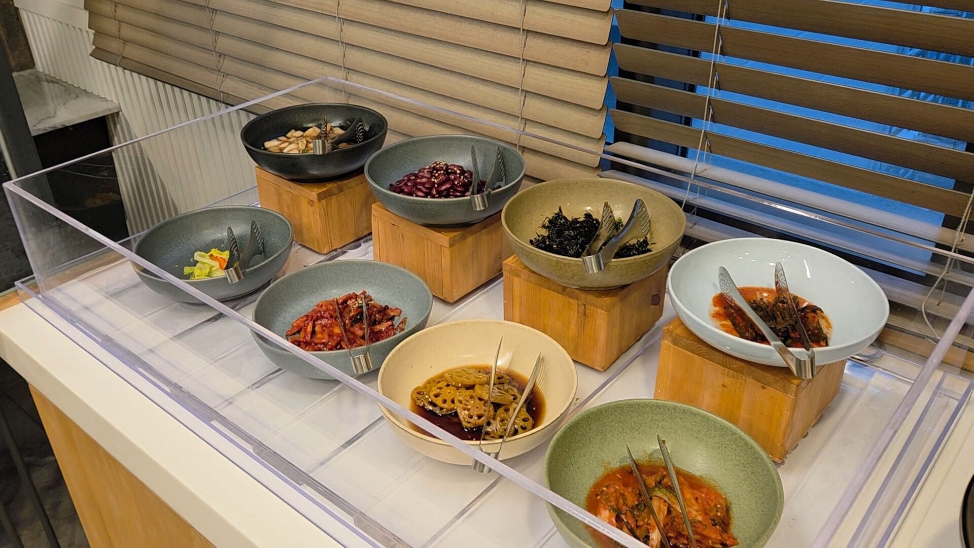 A buffet with various dishes in bowls and wooden containers.