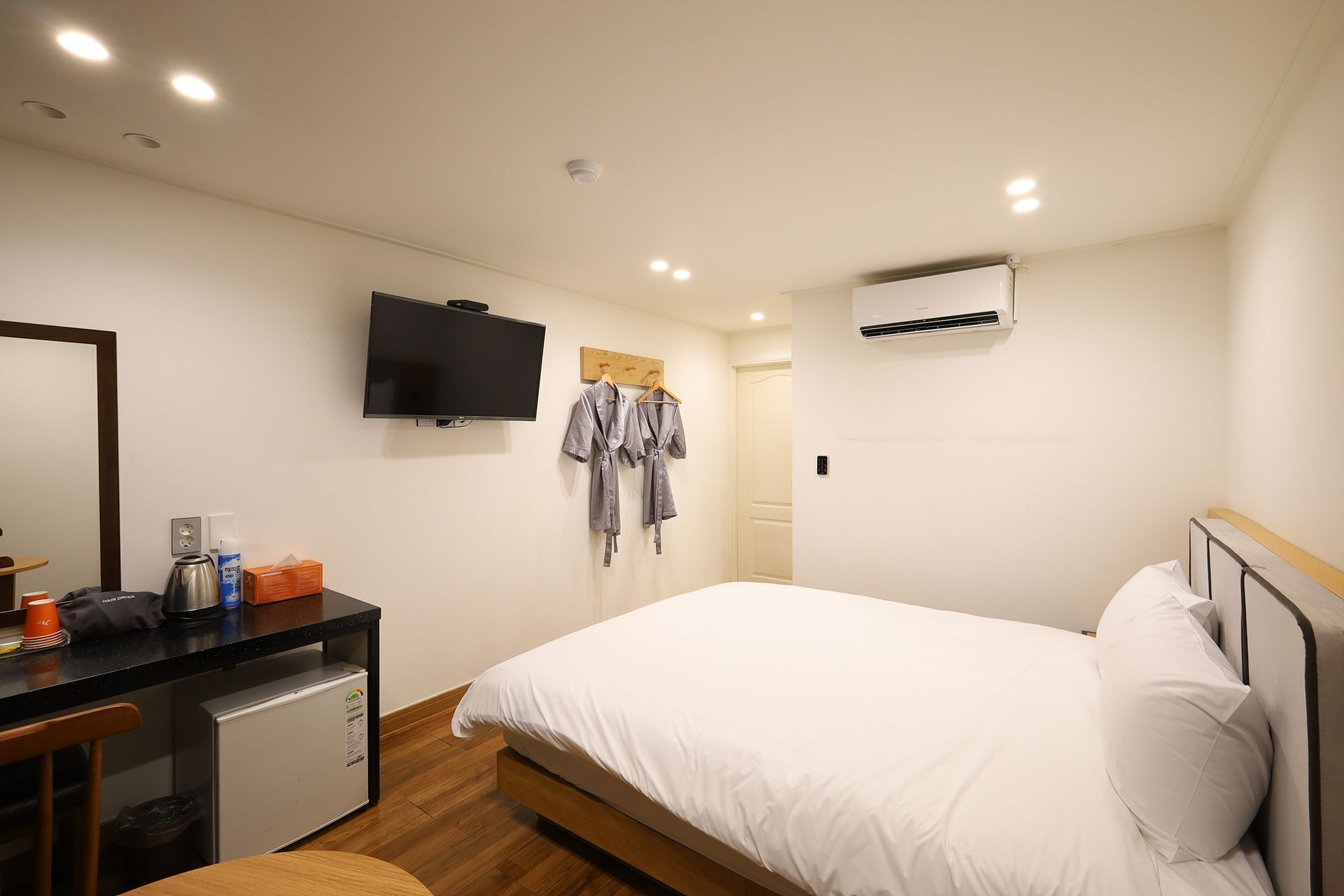 Une chambre d’hôtel comprenant un lit, un bureau avec un ordinateur, une télévision et une armoire.