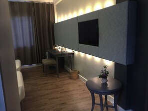 A compact room with a desk, a chair, a small round table with a vase, and a curtain. - R.S. Hotel (Kanchanaburi)
