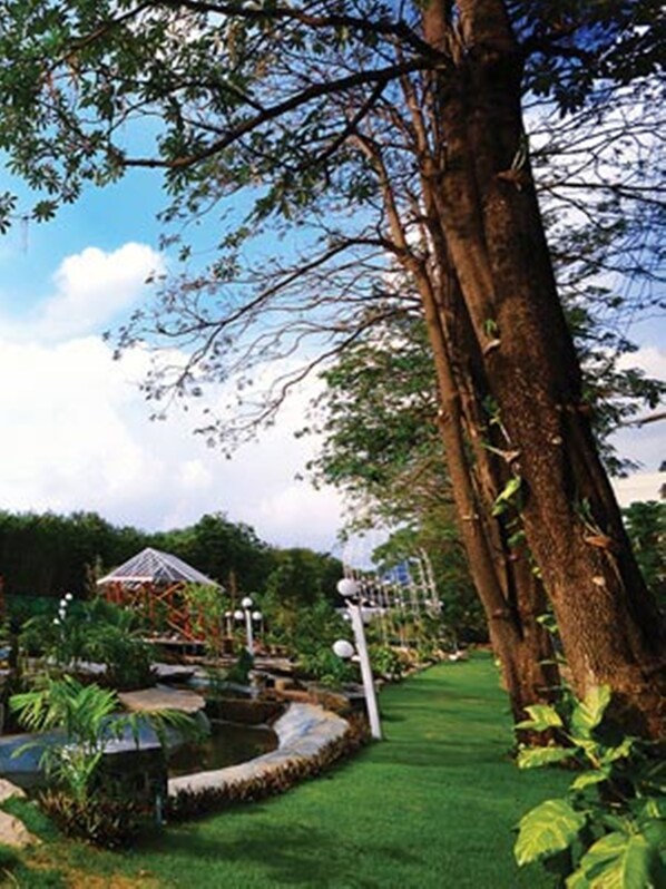 Un jardín con un estanque, un pabellón y un árbol grande.