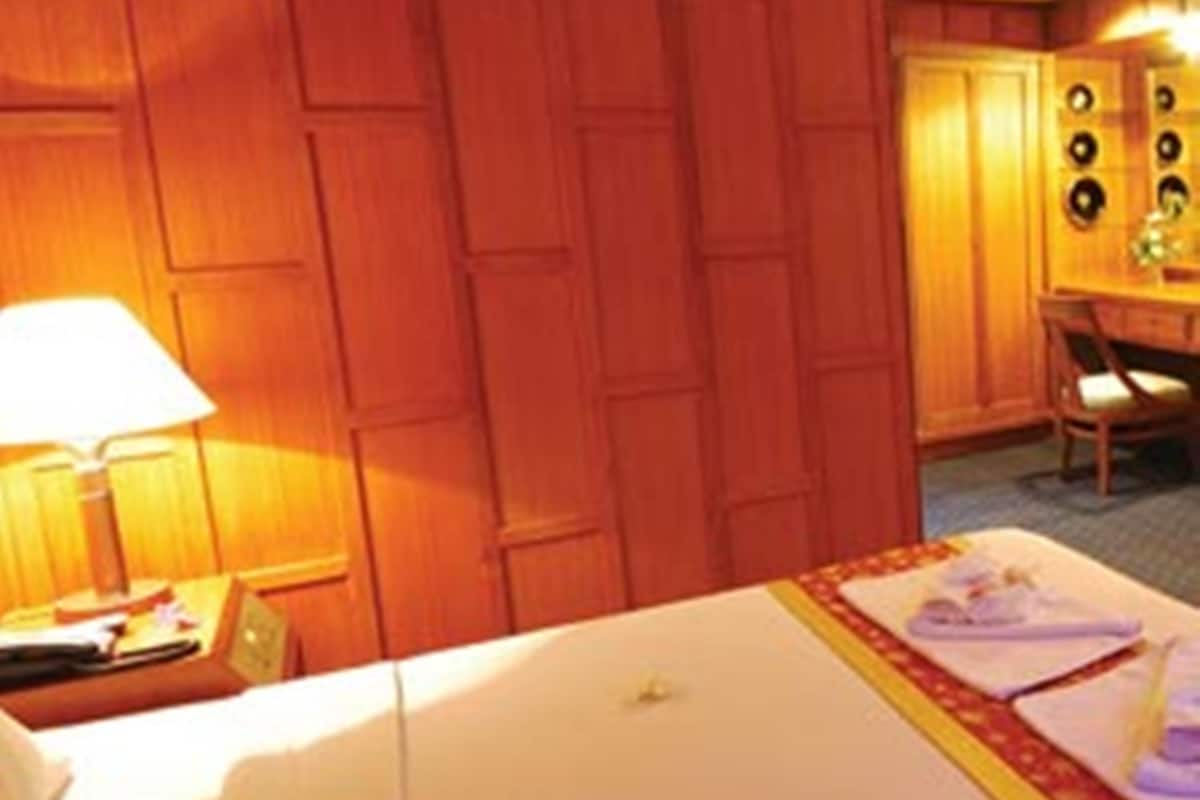 Quarto de hotel com cama, escrivaninha, cadeira e luminária.