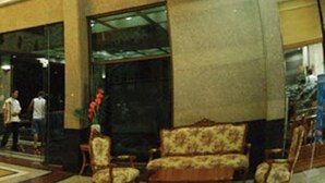 A lobby with a reception desk, seating area, and a staircase leading to upper floors. - R.S. Hotel (Kanchanaburi)