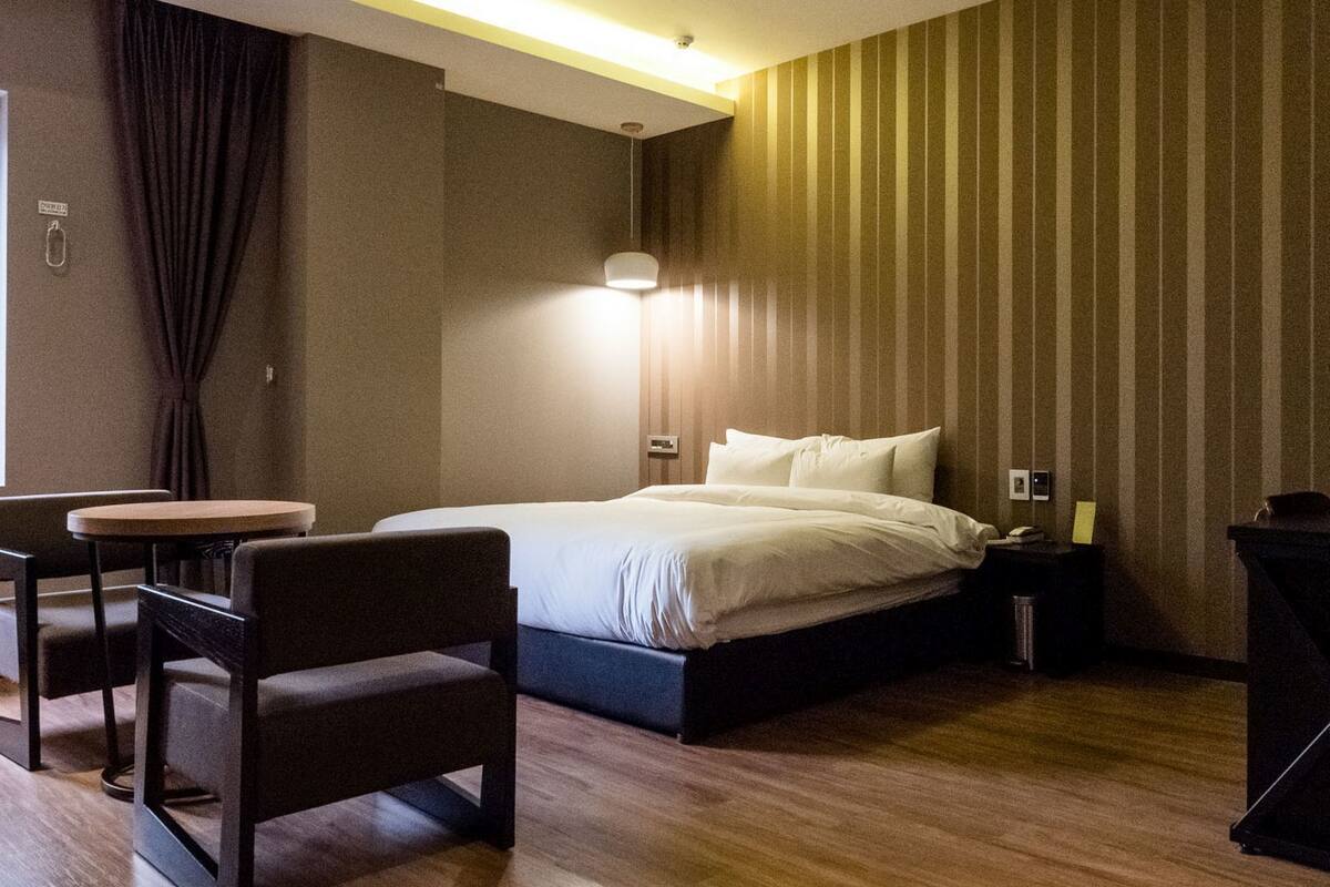 Une chambre d’hôtel comprenant un lit, un bureau, une chaise, une table de chevet et une lampe.