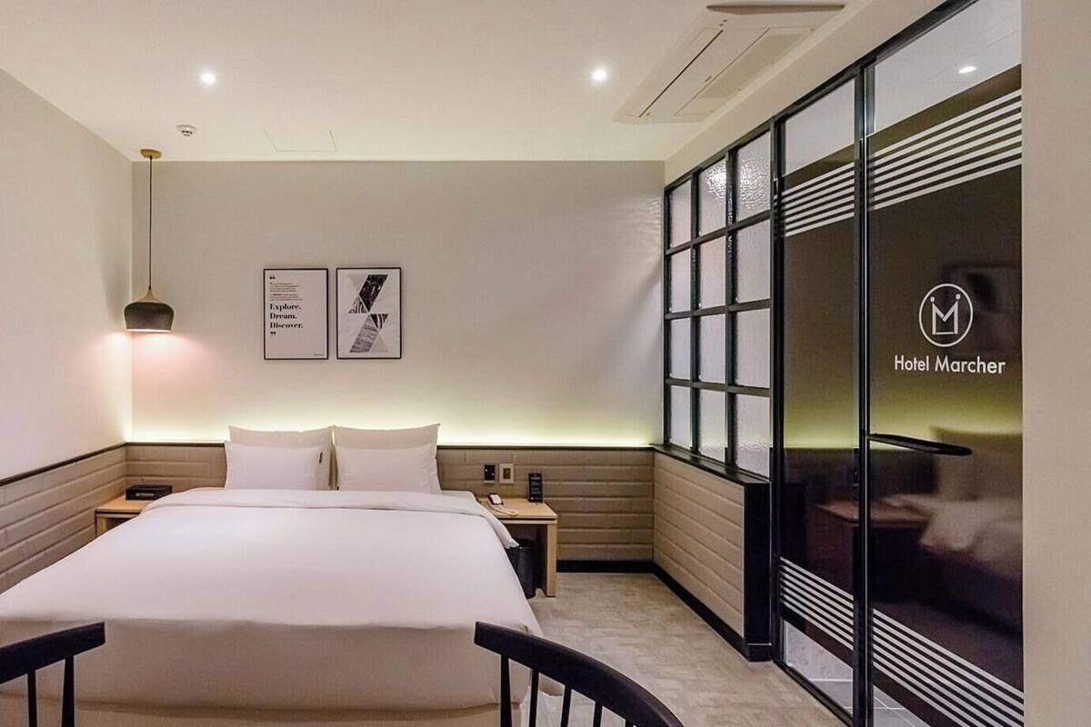 Une chambre d’hôtel avec un lit, des tables de chevet, un bureau et une grande fenêtre donnant sur un beau paysage.