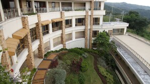 A multi-story building with a curved roof, balconies, and a landscaped courtyard. - Timberland Highlands Resort (San Mateo)