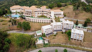 A large resort with multiple buildings, a swimming pool, and a hilly backdrop. - Timberland Highlands Resort (San Mateo)