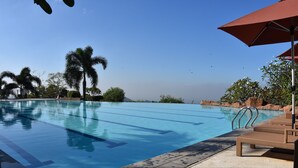 A swimming pool with clear blue water, surrounded by palm trees and lounge chairs. - Timberland Highlands Resort (San Mateo)