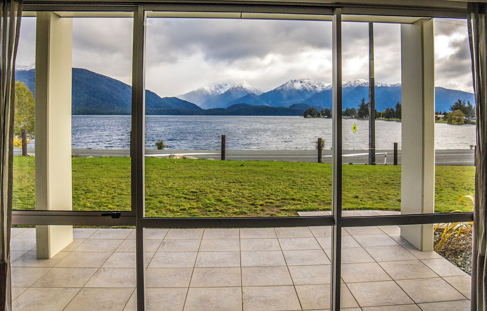 A view through a window of a lake with mountains in the background.