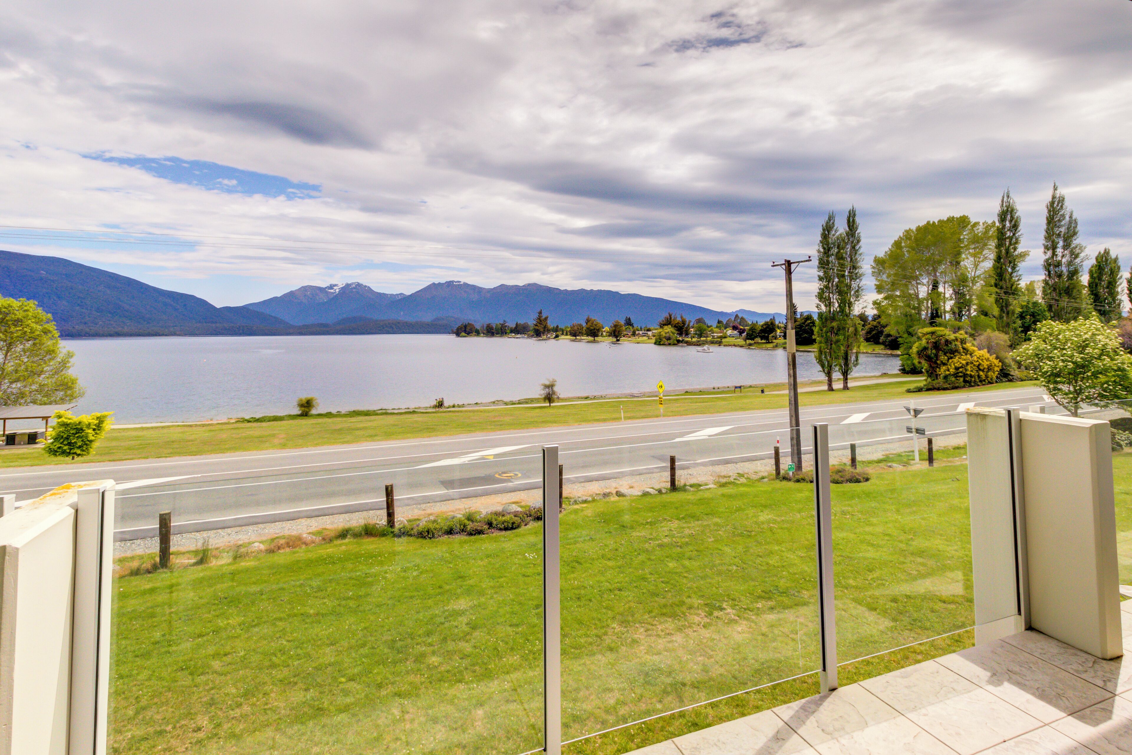 A view of a road leading to a body of water with mountains in the background.