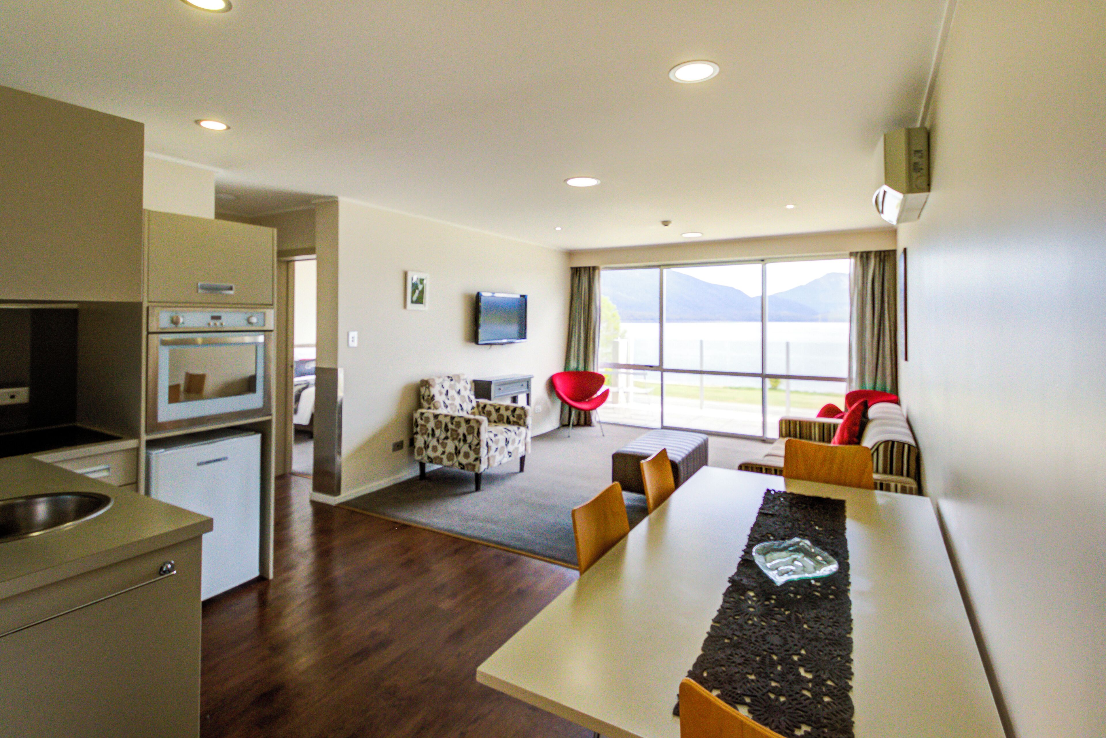 A modern kitchen with built-in appliances, a dining area with a long table, and a view of the outdoors.