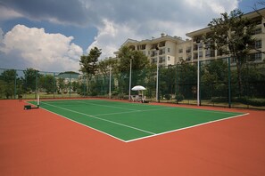 A tennis court with a net, surrounded by a green fence and trees. - Country Garden Phoenix Hot Spring Hotel Xianning (Xianning)