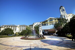 A hotel courtyard with a fountain, a clock tower, and a large building with multiple floors and balconies. - Country Garden Phoenix Hot Spring Hotel Xianning (Xianning)