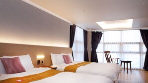 A hotel room with two beds, a wooden headboard, a small table, and a chair. - Ariana Hotel (Daegu)