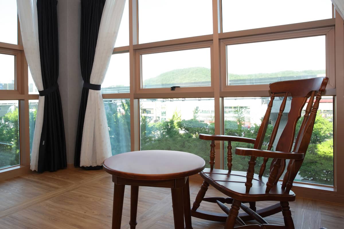 A room with a large window, a wooden chair, and a small table.