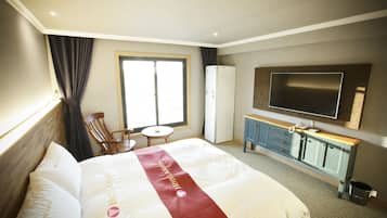 A hotel room with a bed, a TV, a desk, and a chair.