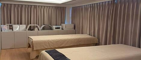 Una habitación de hotel con dos camas, un escritorio, una silla y una ventana con cortinas.