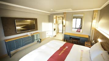 A hotel room with a large bed, a desk, a mirror, and a television on the wall.