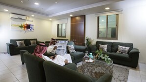 A modern living room with green sofas, a coffee table, and a large window. - Palms Lily Hotel Suites (Al-Hofuf)
