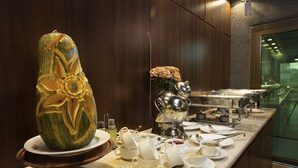 A buffet setup with a carved watermelon centerpiece, a variety of dishes, and a tea service. - Palms Lily Hotel Suites (Al-Hofuf)