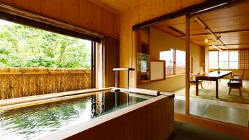 A traditional Japanese room with tatami flooring, a wooden interior, and a view of a bamboo fence outside.