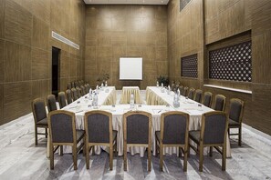 Une salle de conférence équipée d’une longue table, de chaises, d’un écran de projection et d’un panneau décoratif au mur.