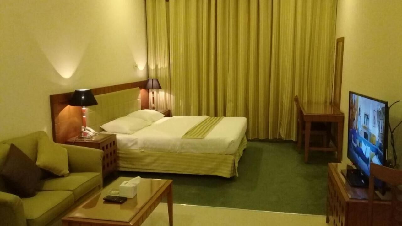 A hotel room with a bed, a sofa, a TV, and a desk.