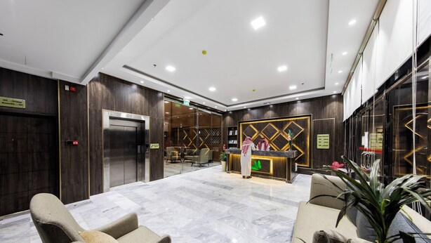 A hotel lobby with a reception desk, seating area, and an elevator. - Lily Hotel Suite Hofuf (Al-Hofuf)
