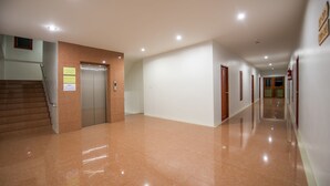 A clean, well-lit hallway with a polished floor, a staircase, and an elevator. - Doungta Anda Hotel (Krabi)