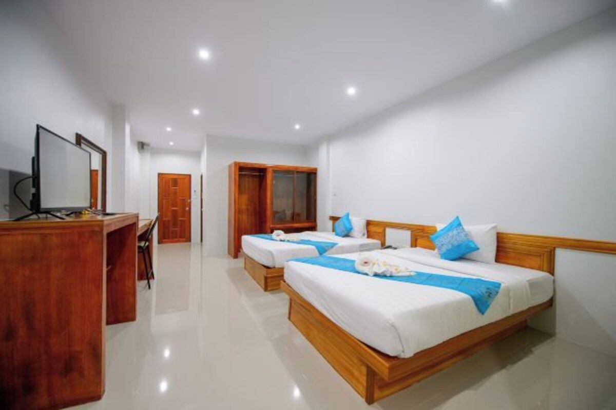 A hotel room with two beds, a wooden desk, a wardrobe, and a mirror.