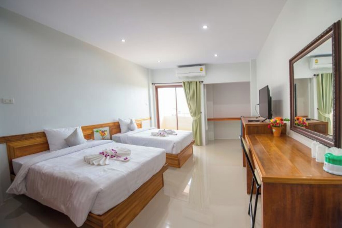 A hotel room with two beds, a wooden desk, a TV, and a large mirror.