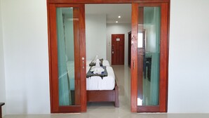 A hotel room with a bed, a wooden wardrobe, and a bathroom visible through a glass door. - Doungta Anda Hotel (Krabi)