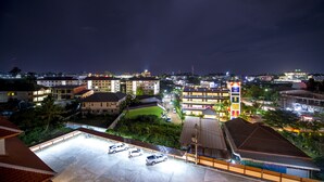 A nighttime view of a hotel with multiple buildings, a parking lot with several cars, and a well-lit sports field. - Doungta Anda Hotel (Krabi)
