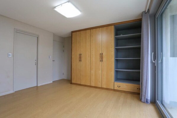 A room with a wooden wardrobe, a sliding glass door, and a light-colored floor. - Huebean Pension (Pyeongchang)