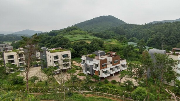 Zona residencial con edificios modernos, espacios verdes y un paisaje montañoso al fondo.