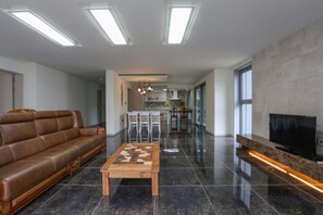 A modern living room with a brown leather sofa, a wooden coffee table, and a flat-screen TV on a stand.