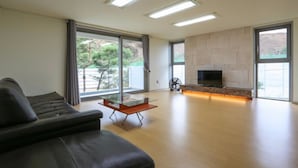 Una sala de estar moderna con un sofá, una mesa de centro de cristal, una chimenea y ventanas grandes.
