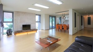 Una amplia sala de estar con una mesa de centro de vidrio, una chimenea y un comedor con sillas.