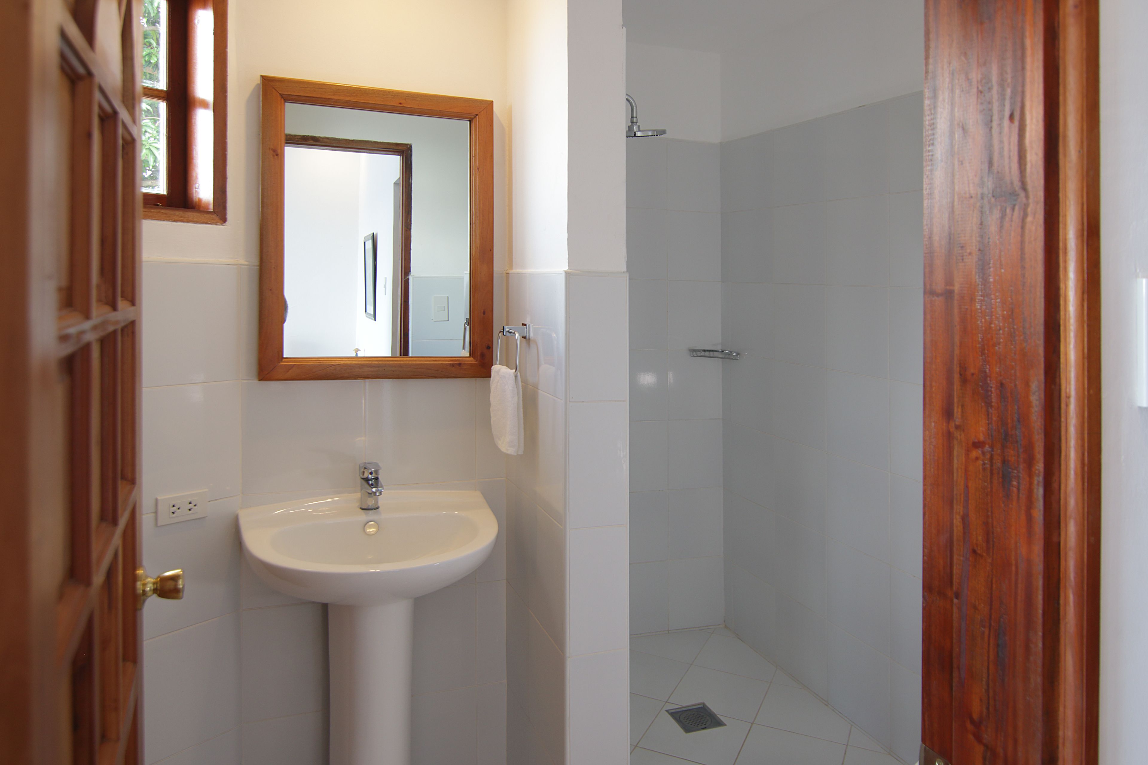 A bathroom with a white sink, a mirror, and a shower.
