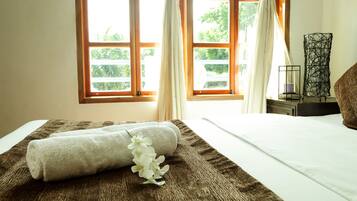 A neatly made bed with a brown textured bedspread and a rolled white towel.