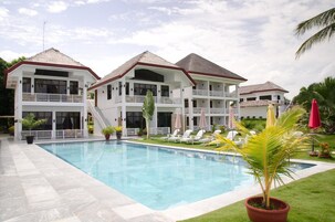 Un resort con piscina, varios balcones y un césped bien cuidado.