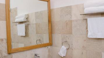 Une salle de bain avec un lavabo sur colonne, un miroir avec un cadre en bois et un porte-serviettes.