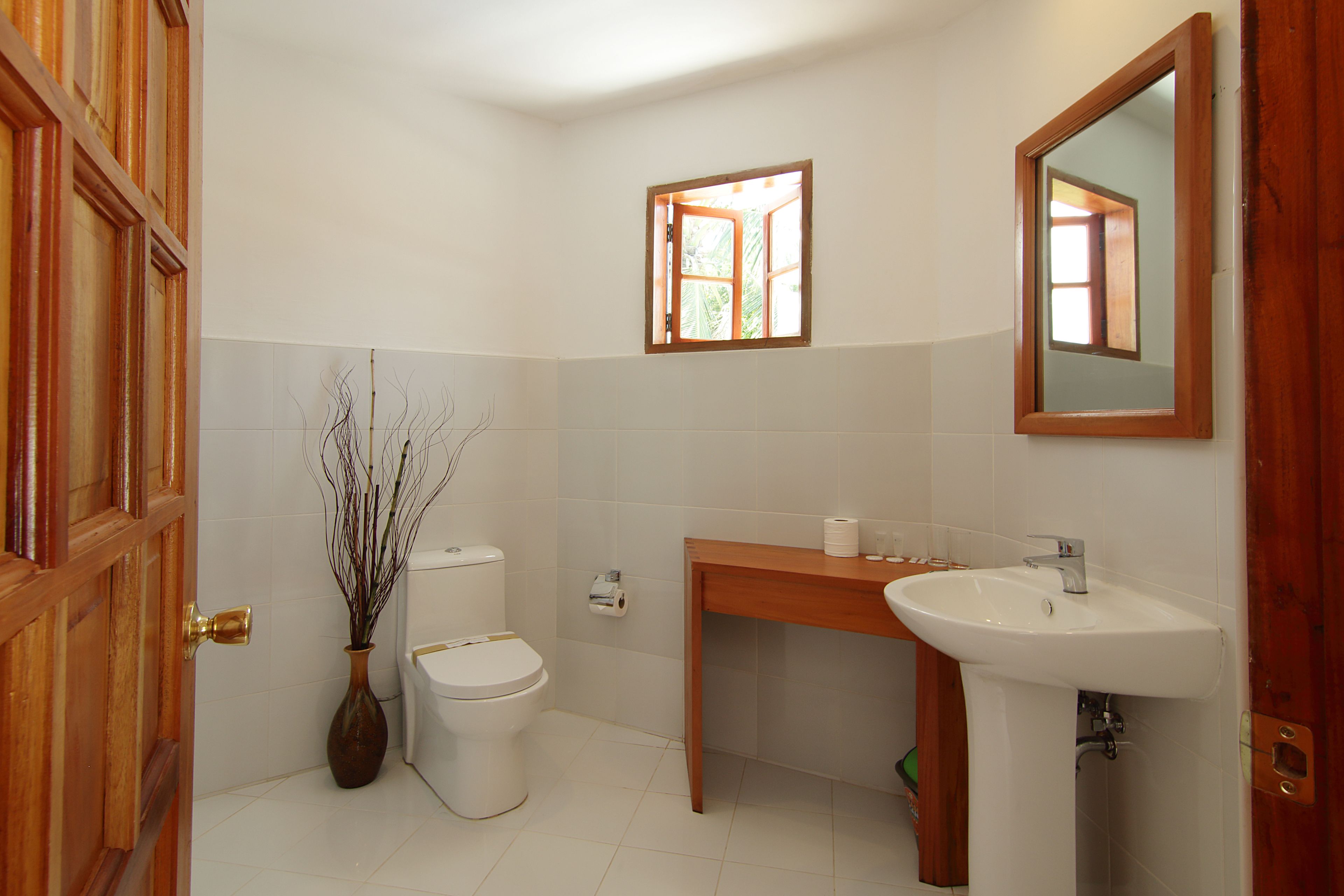 A bathroom with a toilet, a sink, a mirror, and a window.