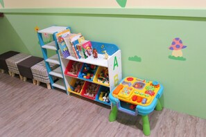 A children's play area with a bookshelf labeled 'A' and 'B', a small table with toys, and a green wall with a mushroom decoration. - Bryan Southern Villages (Tainan)