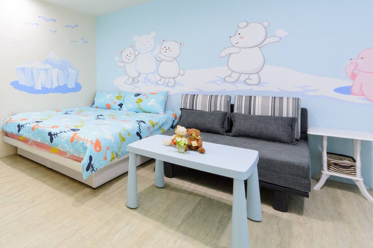 A child's bedroom with a bed, a sofa, a small table, and a wall mural.